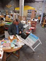 Mann in Werkstatt beklebt weißen Stuhl mit bunten Streifen. Foto: Katja Schneider 